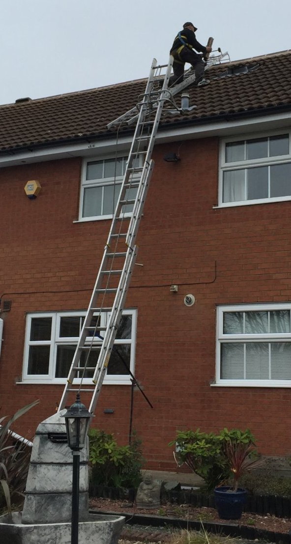 Workman installing a Solatube Daylighting System on a terraced house roof