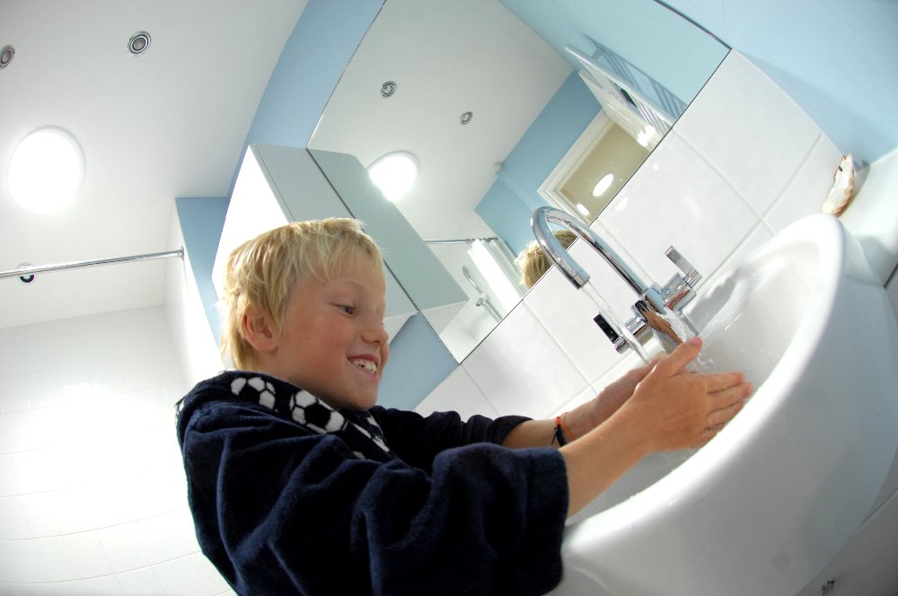 Child washing hands in bathroom lit by daylight from a solatube daylighting system